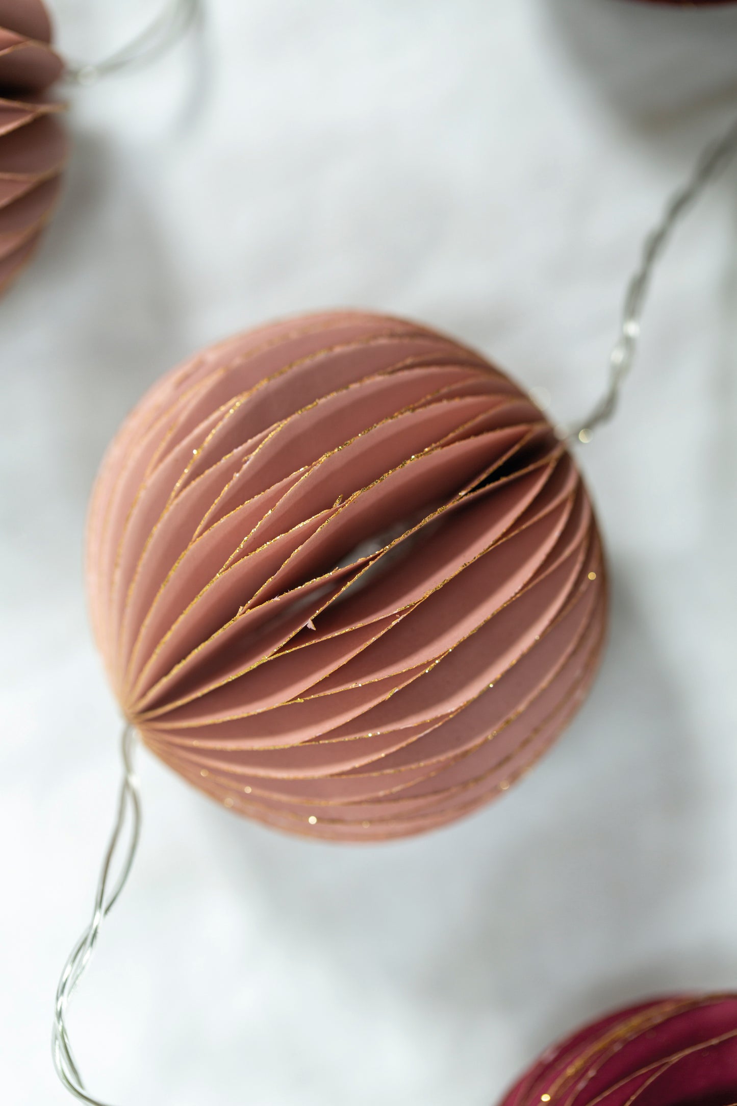 Glitter detail on our ducky pink Christmas garland of fairy lights and paper bauble decorations