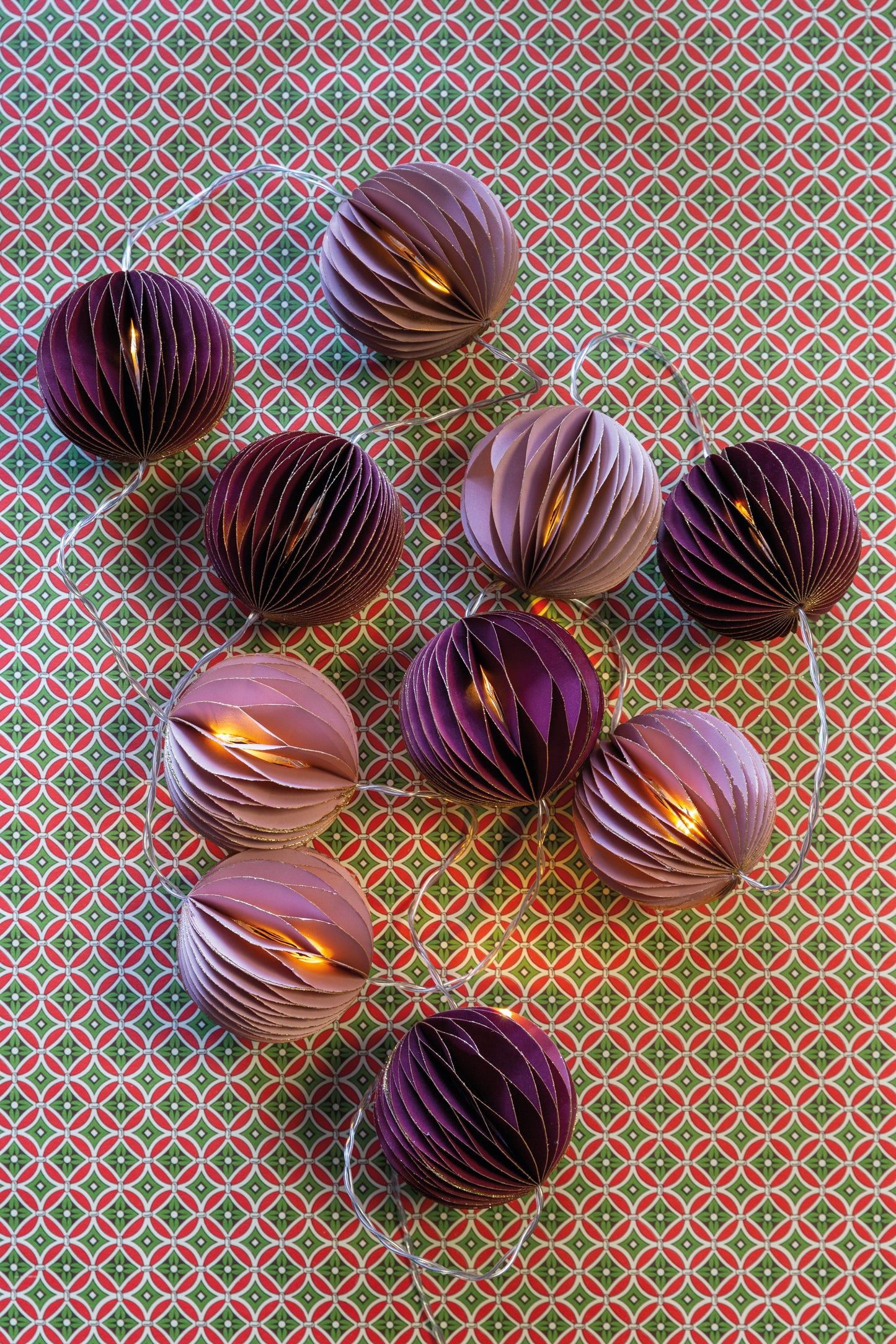 Twinkling lights in our pretty dusky pink and purple Christmas fairy light garland with honeycomb paper baubles