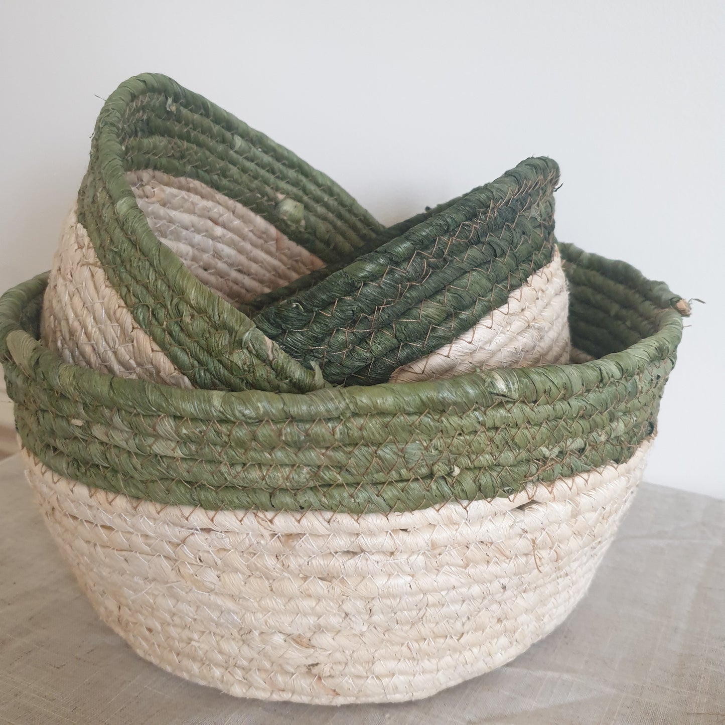 Set of three olive trimmed straw baskets, perfect for adding natural texture and rustic touches to your home interiors