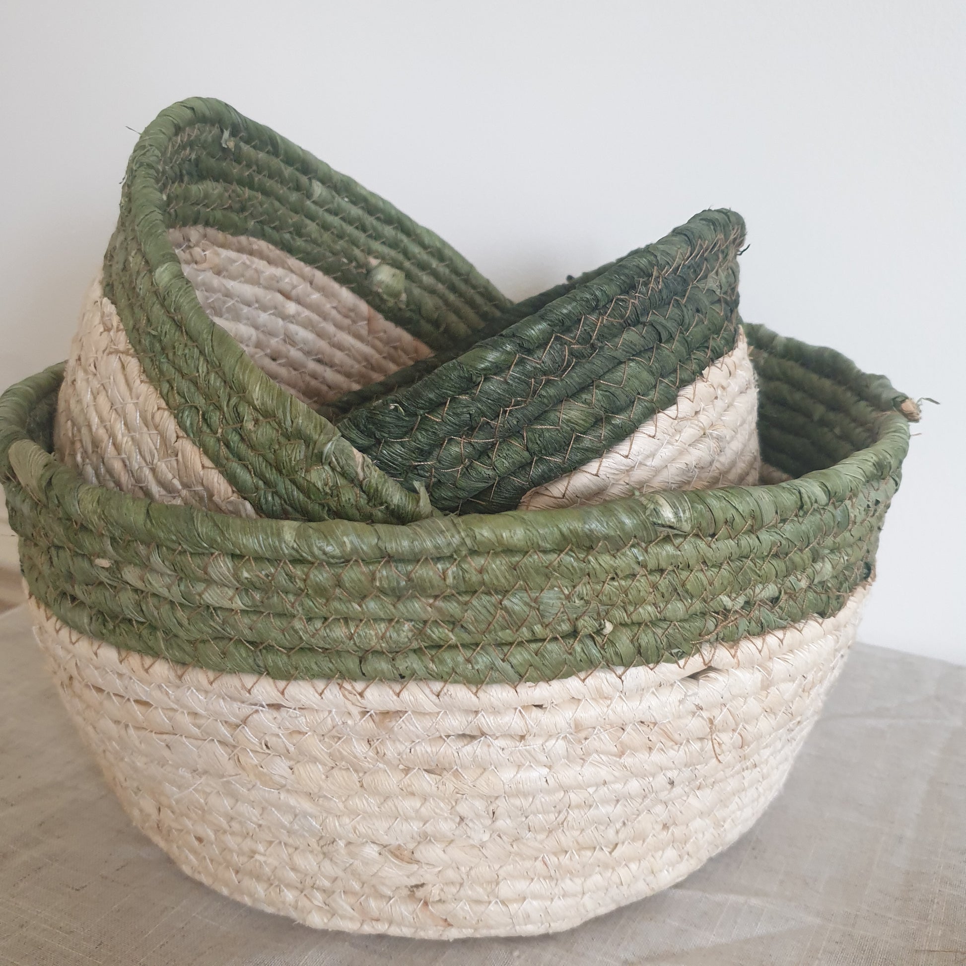 Set of three olive trimmed straw baskets, perfect for adding natural texture and rustic touches to your home interiors