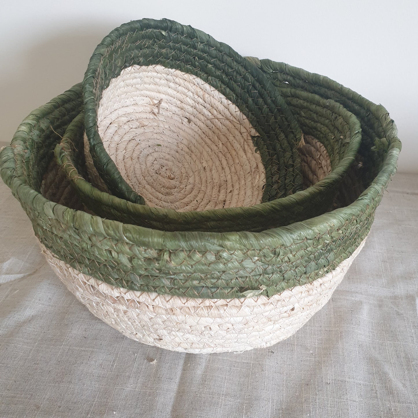 Set of three olive trimmed straw baskets, perfect for adding natural texture and rustic touches to your home interiors