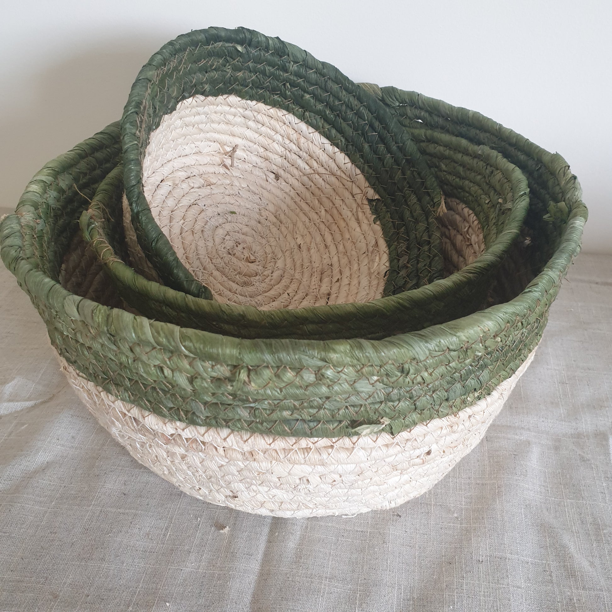 Set of three olive trimmed straw baskets, perfect for adding natural texture and rustic touches to your home interiors