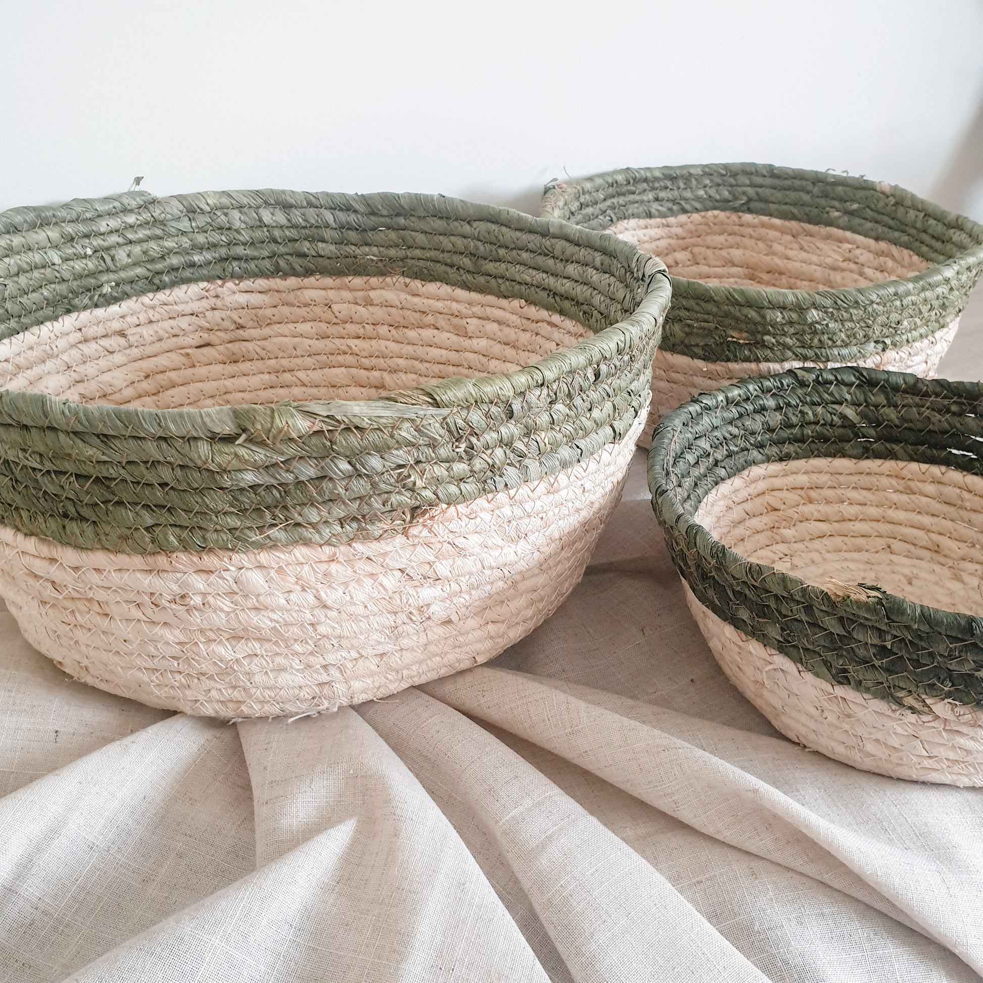 Set of three olive trimmed straw baskets, perfect for adding natural texture and rustic touches to your home interiors