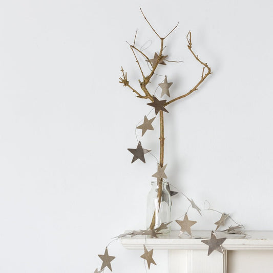 Antiqued Silver Star Garland on branch on mantel piece in vase