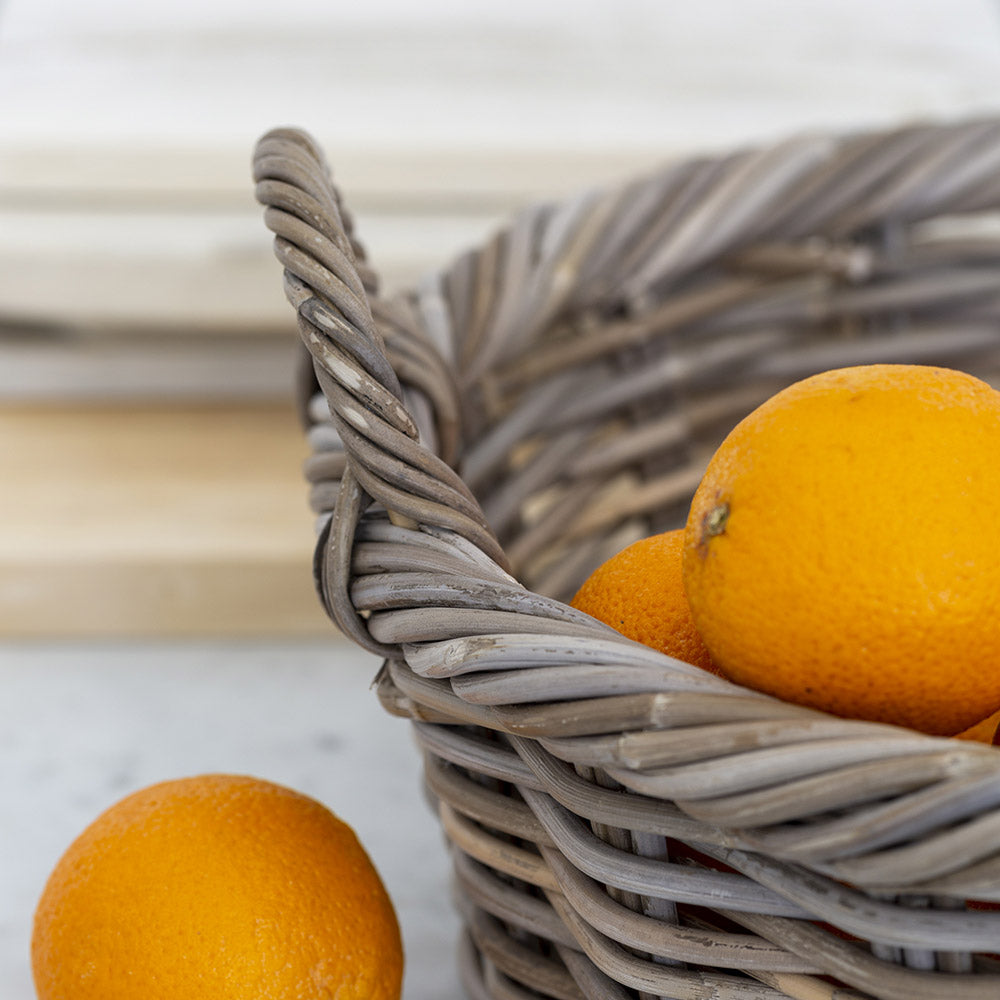 Close up of kubu basket with orange. Pretty, practical twisted rim detail kubu basket for handy storage around your home. Pretty bedroom, kitchen, bathroom storage. Basket with handles, a pretty, versatile and practical storage solution. Kubu basket | Kitchen counter basket | Pretty display basket | Rattan Basket | Rustic home accessory | Modern Country  Home Accessory