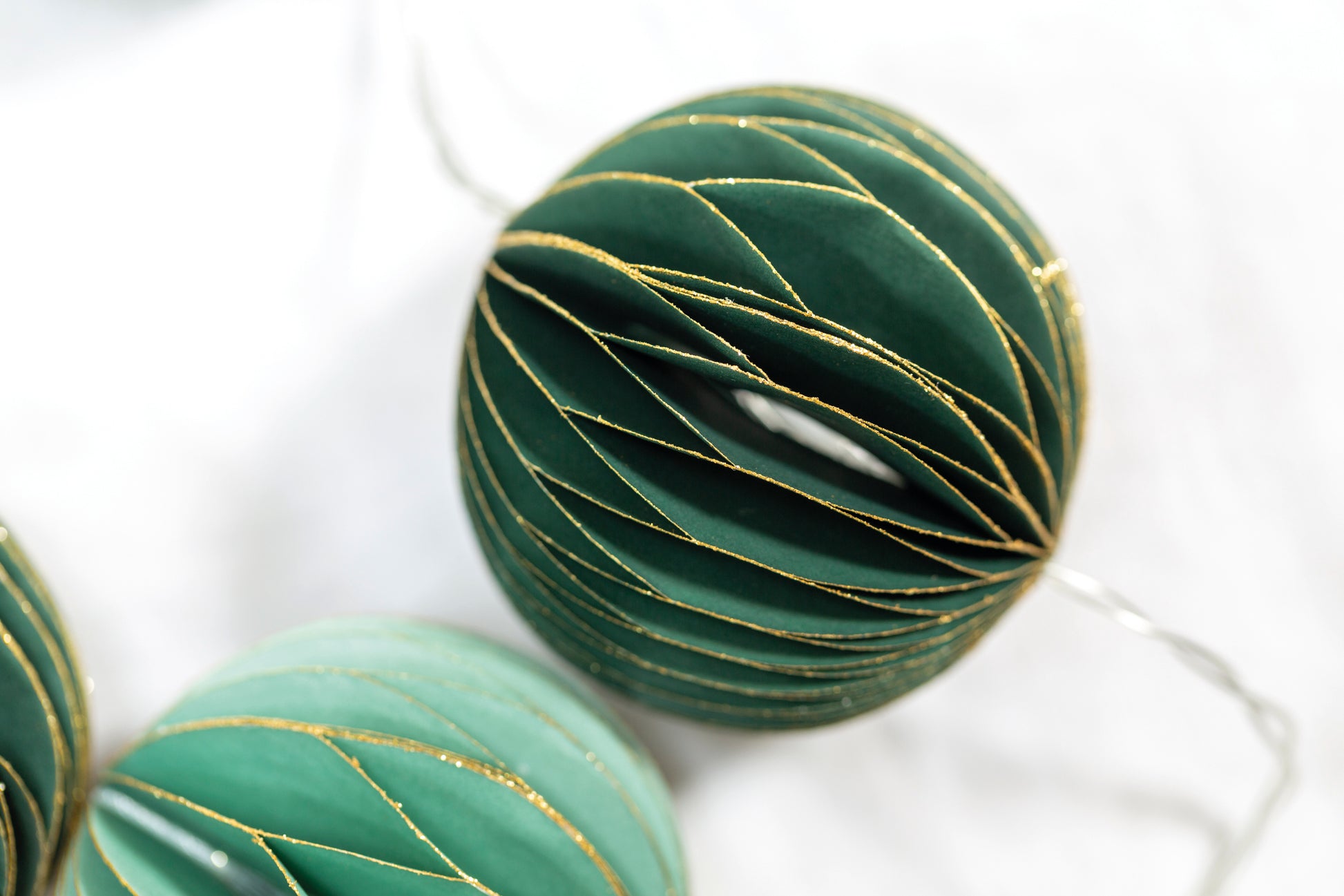 Detail of our emerald green honeycomb bauble on fairy light string with timer. Perfect for Christmas garlands, banisters and mantelpieces