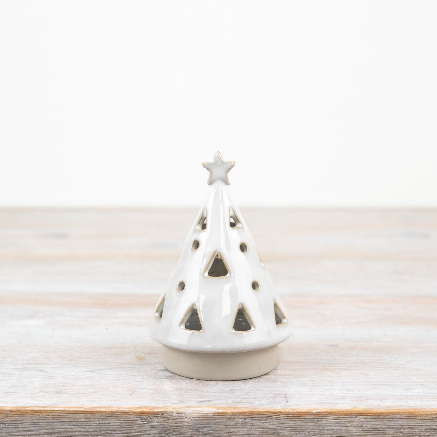 White ceramic Christmas tree with star on top on a wooden surface